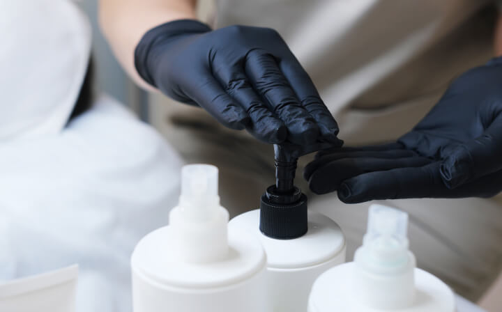 A person using a bottle to get beauty product out