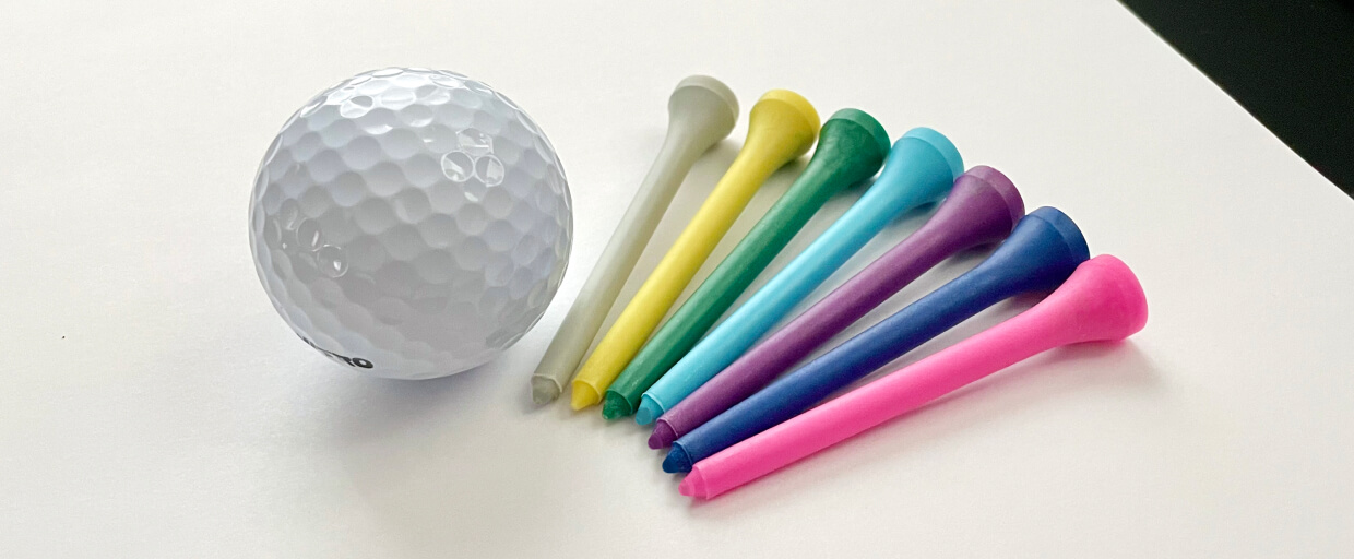 A golf ball next to colorful golf tees made from Verde's bioresins